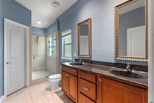 a bathroom with a double vanity sink toilet mirror and shower