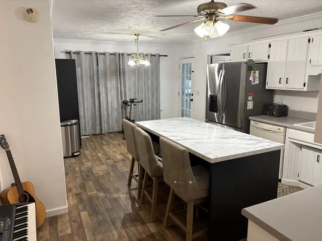 a kitchen with stainless steel appliances kitchen island a table chairs and refrigerator
