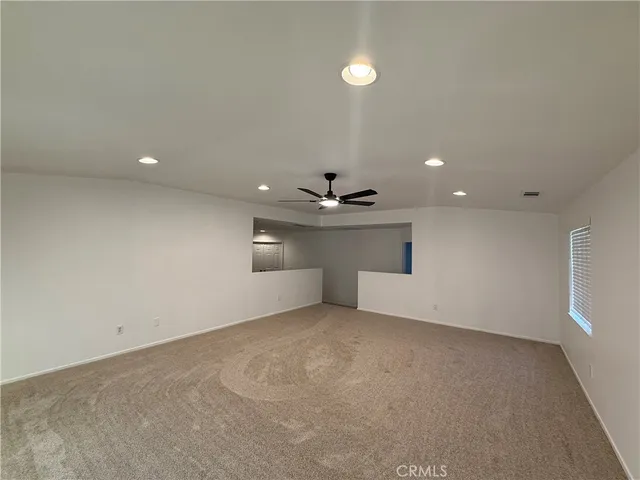 an empty room with a ceiling fan and window