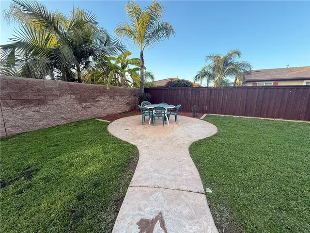 a view of a backyard with table and chairs potted plants and wooden fence