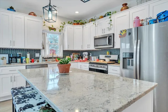 a kitchen with stainless steel appliances granite countertop a refrigerator a stove and a sink with wooden floor