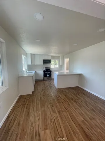 a view of empty room with wooden floor and window
