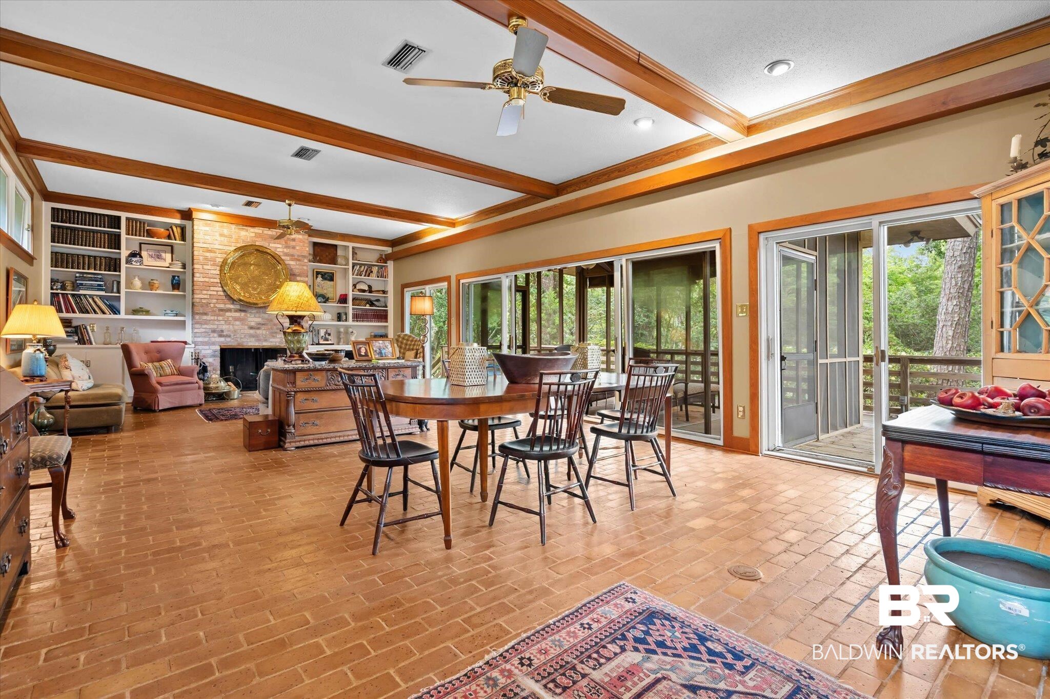 3500 Venetia Road Mobile, AL 36605 - Photo 12 of 56 Spacious interior featuring brick flooring, exposed ceiling beams, a brick fireplace, built-in shelving, and multiple sliding glass doors opening to outdoor spaces