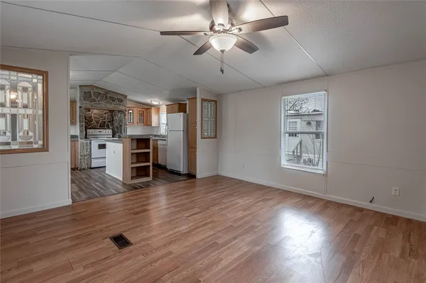 a view of a livingroom with a flat screen tv wooden floor and a ceiling fan