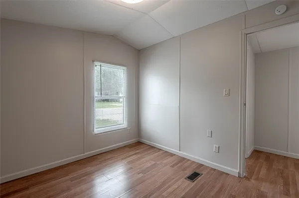 an empty room with wooden floor and window