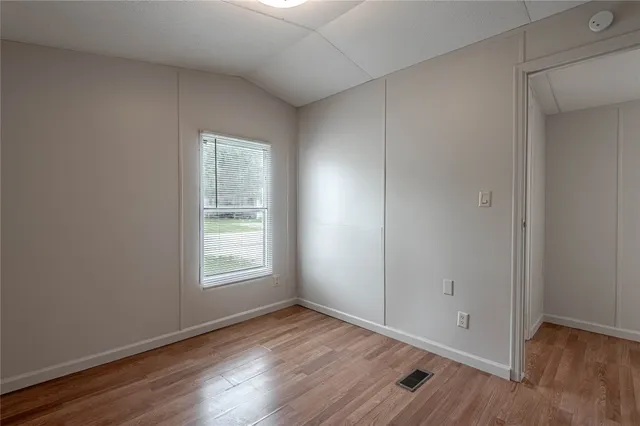 an empty room with wooden floor and window