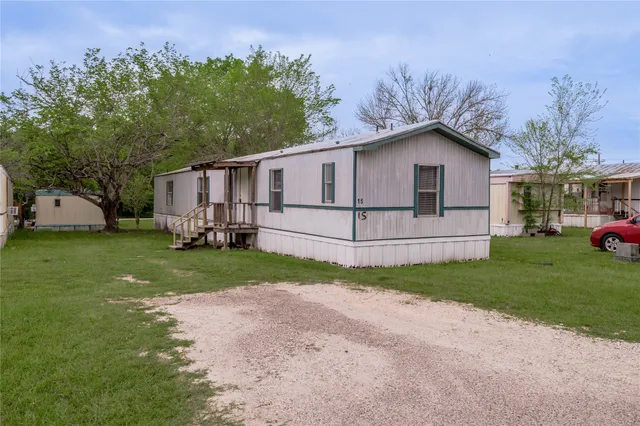 a view of backyard of house with wooden fence and trees