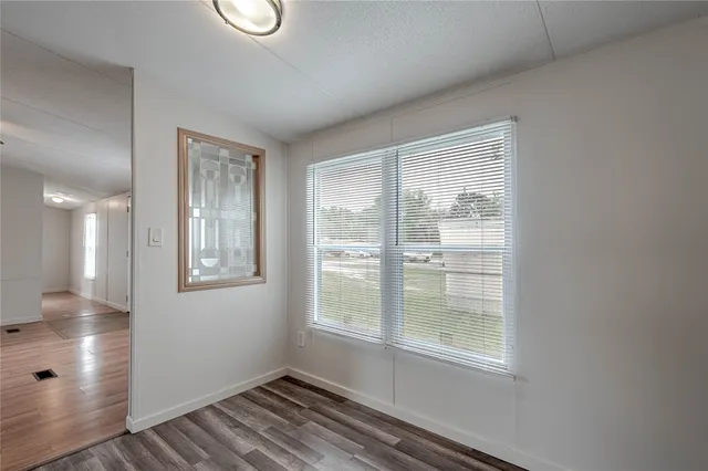 a view of an empty room with wooden floor and a window