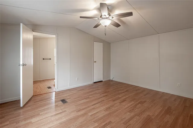 an empty room with wooden floor and ceiling fan