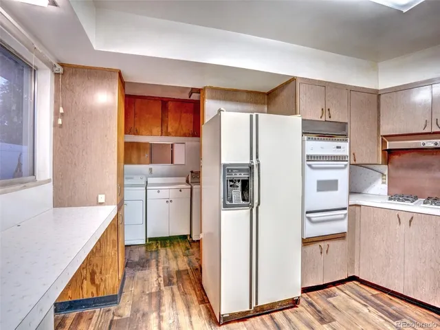 a kitchen with a refrigerator a sink and dishwasher with wooden floor