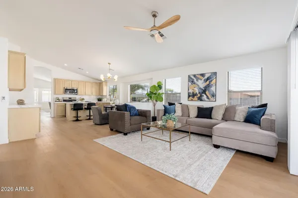 a living room with furniture kitchen view and a chandelier