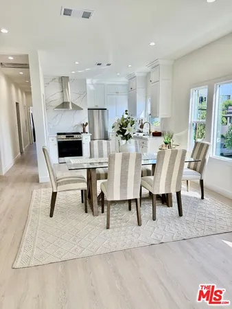 a view of a dining room kitchen with stainless steel appliances kitchen island granite countertop a table and chairs in it