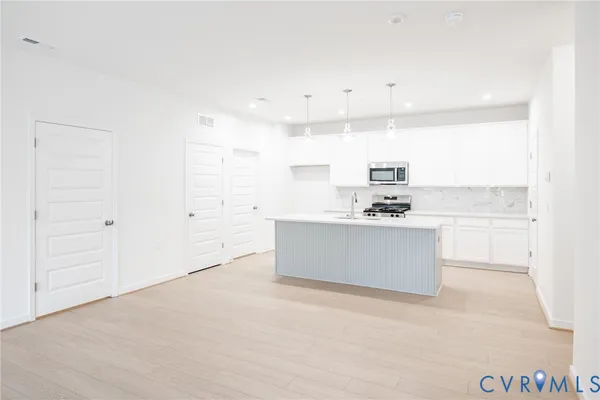 a view of kitchen with kitchen island white cabinets and sink