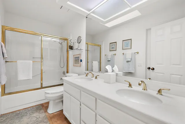 a bathroom with a double vanity sink toilet mirror and shower