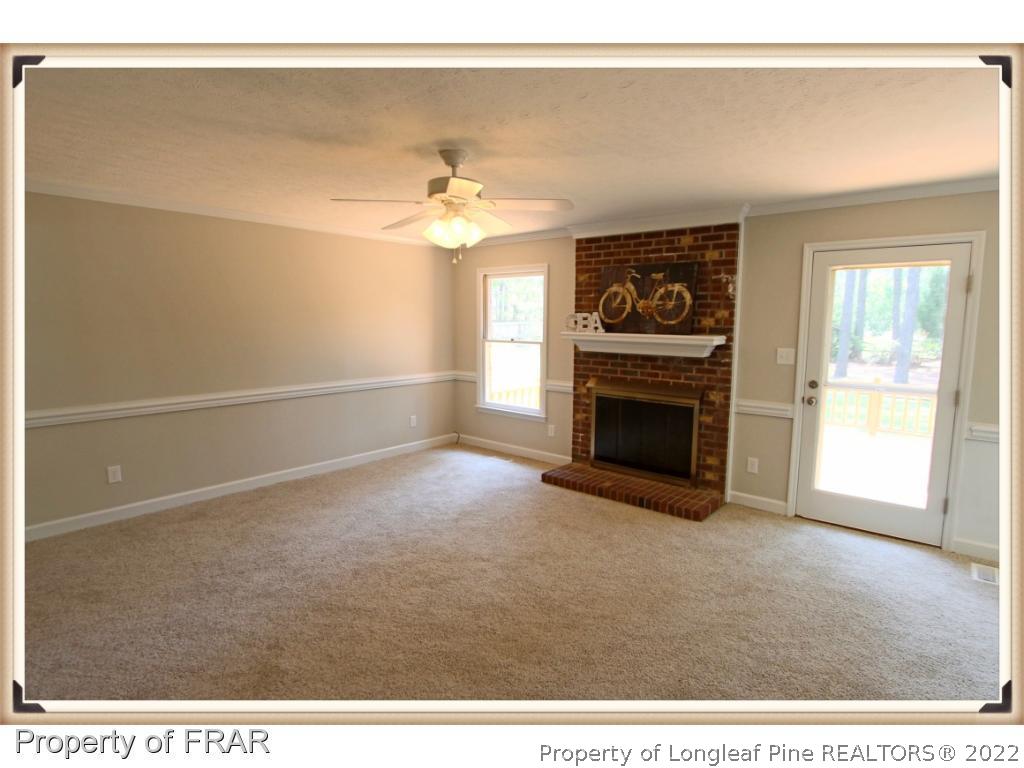 7786 Dragonhead Road Fayetteville, NC 28311 - Photo 14 of 33 a view of a livingroom with a fireplace a ceiling fan and wooden floor