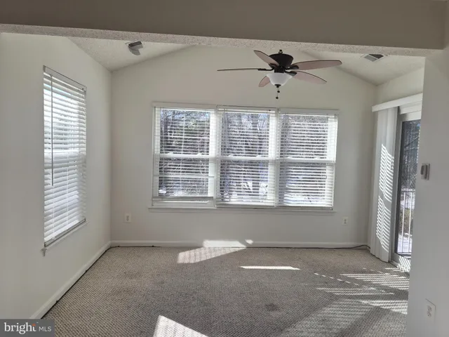 an empty room with windows and ceiling fan