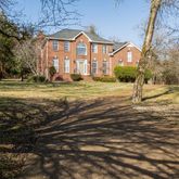 a view of a big house with a big yard and large trees