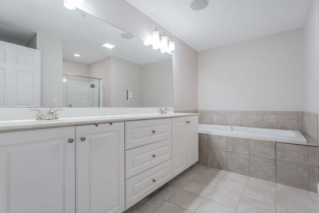 22 Highland Road, Unit 31 Raynham, MA 02767 - Photo 13 of 28 a bathroom with a double vanity sink a mirror and a bathtub