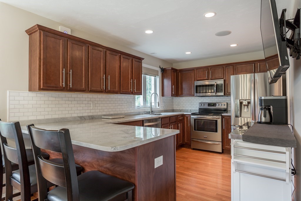 22 Highland Road, Unit 31 Raynham, MA 02767 - Photo 7 of 28 a kitchen with granite countertop a stove top oven microwave and refrigerator