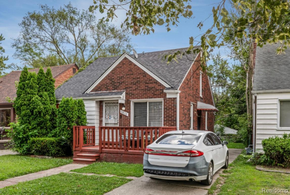 10878 Balfour Road Detroit, MI 48224 - Photo 3 of 14 Bungalow-style home featuring a front lawn, roof with shingles, a deck, and brick siding