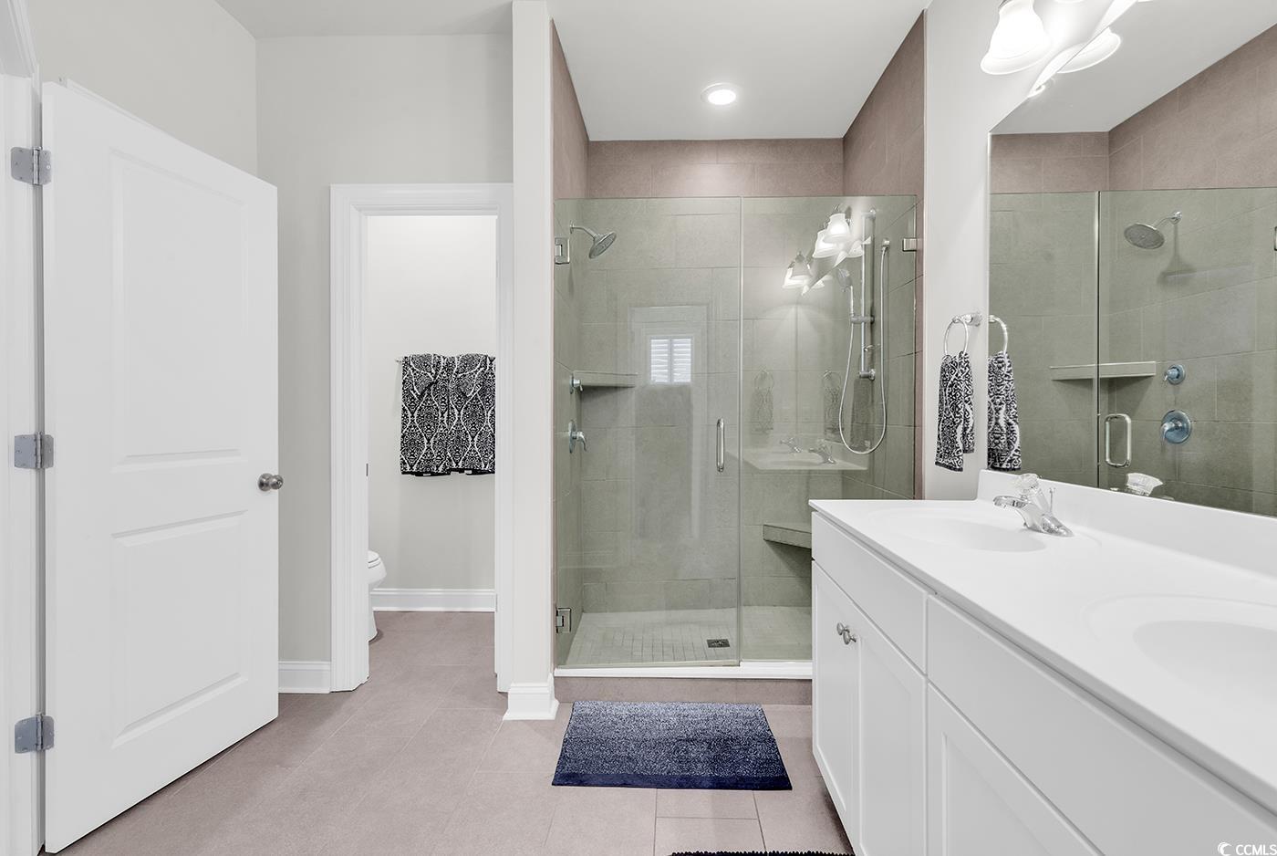 535 Chanted Drive Murrells Inlet, SC 29576 - Photo 17 of 37 Full bathroom featuring double vanity, light tile patterned floors, and a shower stall