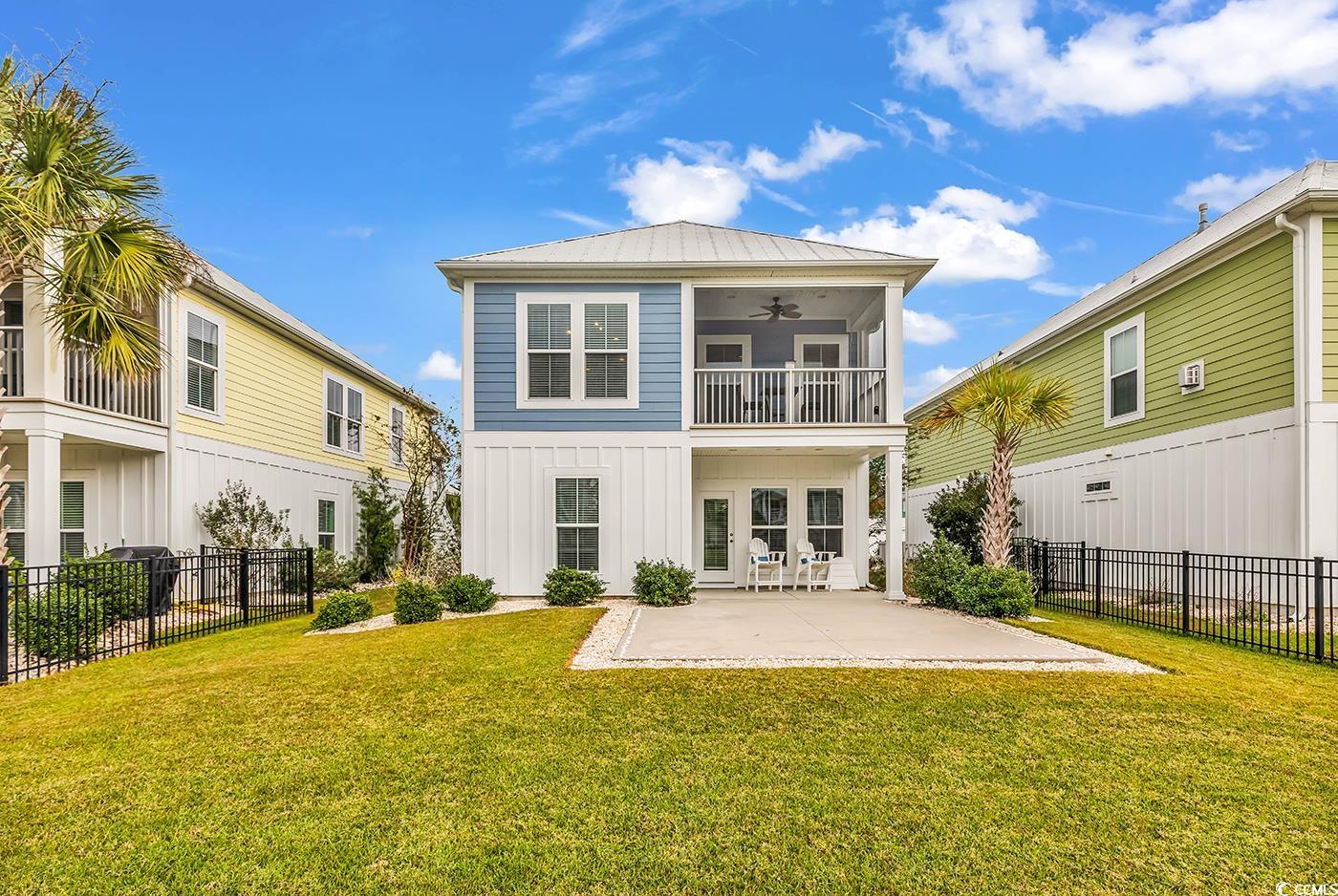 535 Chanted Drive Murrells Inlet, SC 29576 - Photo 29 of 37 Rear view of house with a ceiling fan, a fenced backyard, a balcony, board and batten siding, and a metal roof