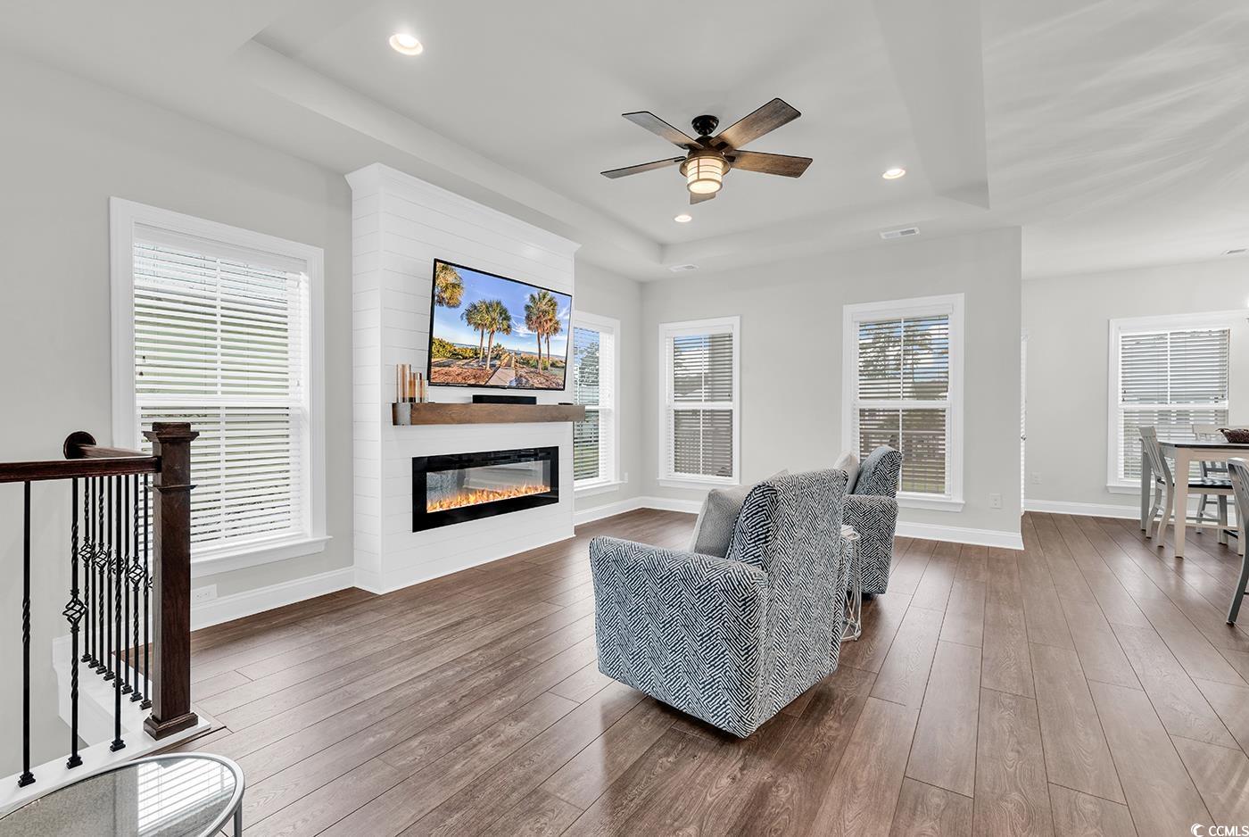 535 Chanted Drive Murrells Inlet, SC 29576 - Photo 3 of 37 Living area with dark wood-type flooring, a tray ceiling, recessed lighting, a glass covered fireplace, and ceiling fan