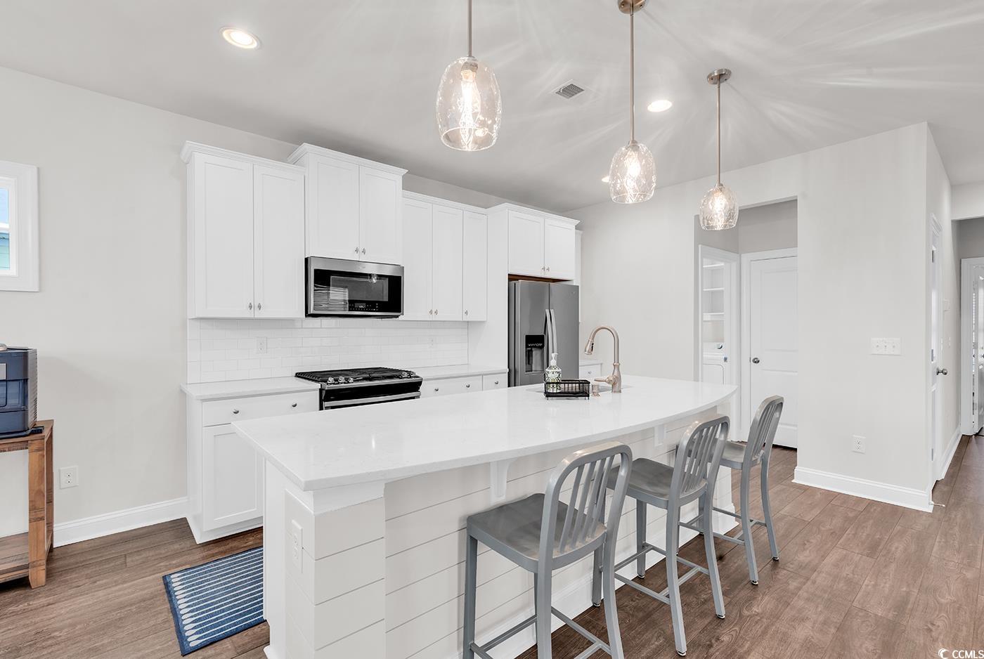 535 Chanted Drive Murrells Inlet, SC 29576 - Photo 5 of 37 Kitchen featuring tasteful backsplash, a kitchen breakfast bar, white cabinets, appliances with stainless steel finishes, and dark wood-style flooring