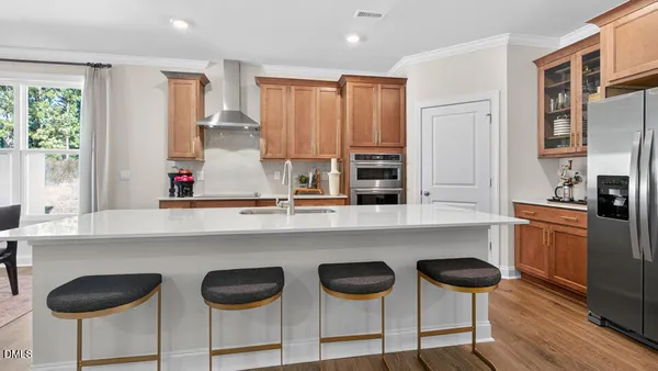 a kitchen with stainless steel appliances a stove a sink and chairs in it