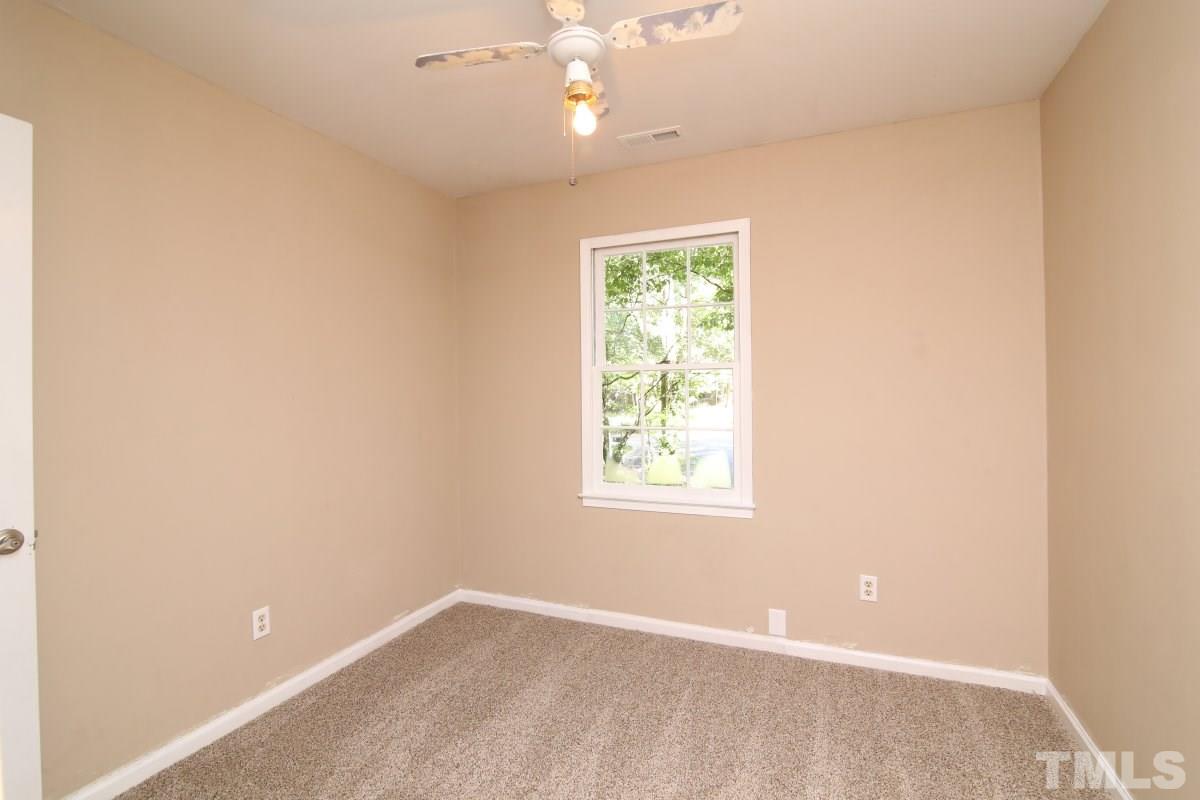 7700 Greentree Court Raleigh, NC 27615 - Photo 21 of 25 an empty room with a chandelier fan and windows