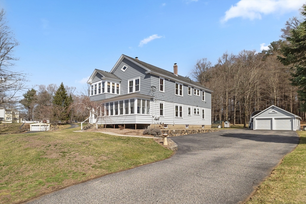 183 Pleasant Street, Unit 2 Grafton, MA 01560 - Photo 2 of 34 a view of a house with a big yard and large trees