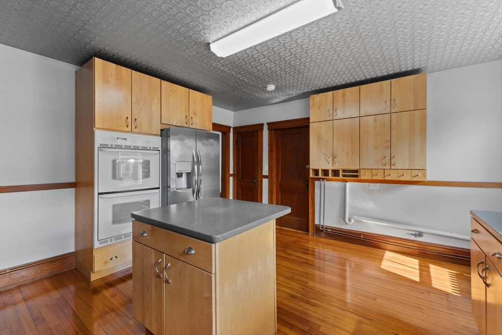 183 Pleasant Street, Unit 2 Grafton, MA 01560 - Photo 6 of 34 a kitchen with stainless steel appliances granite countertop a refrigerator a sink dishwasher and wooden cabinets with wooden floor
