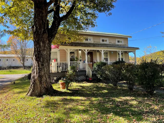 a view of a white house with a large pool and large trees