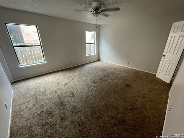 an empty room with windows and fan