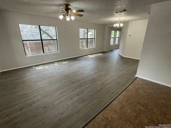 an empty room with wooden floor chandelier and windows