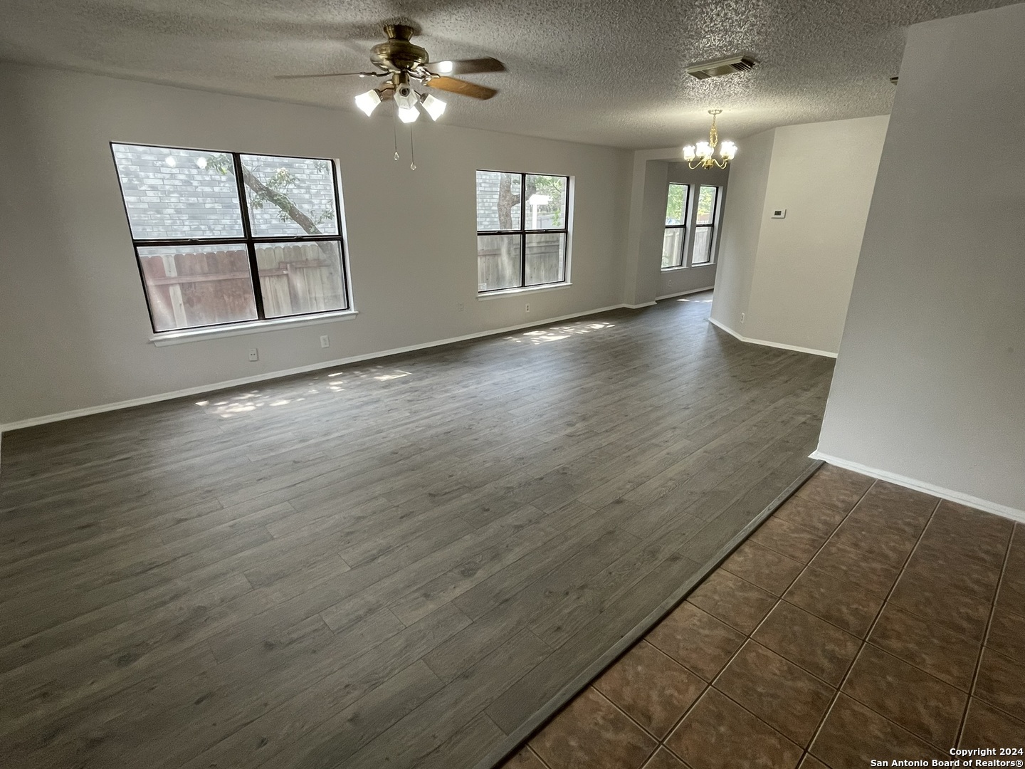9235 Ridge Post San Antonio, TX 78250 - Photo 4 of 30 an empty room with wooden floor chandelier and windows
