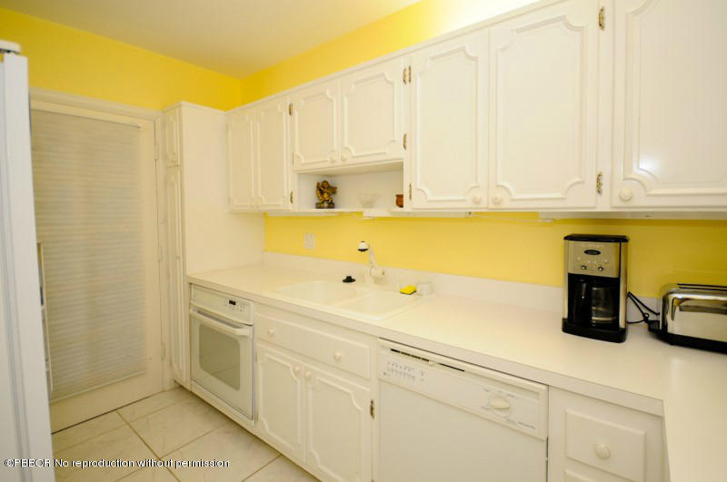 2195 Ibis Isle Road, Unit 6 Palm Beach, FL 33480 - Photo 9 of 15 a kitchen with stainless steel appliances white cabinets and a refrigerator