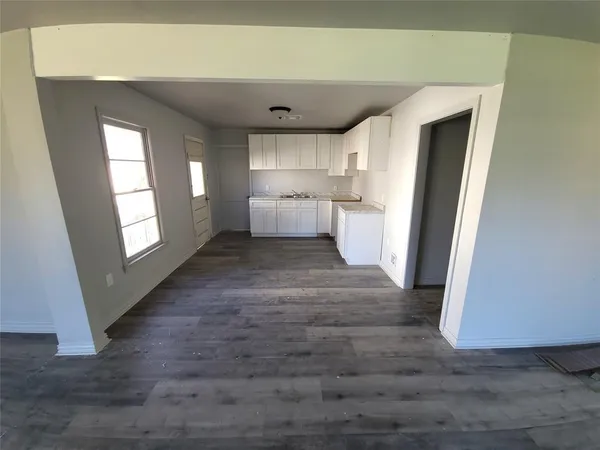 a view of empty room with wooden floor and window