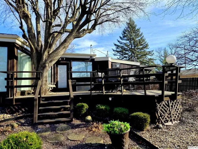 a front view of a house with garden and trees