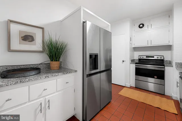 a kitchen with granite countertop a refrigerator and a stove top oven
