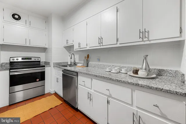 a kitchen with granite countertop white cabinets and stainless steel appliances