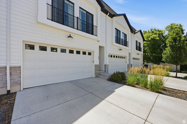 57 McCall Ln. Farmington, UT 84025 - Photo 1 of 36 Modern townhome exterior featuring white siding, black-framed windows, and stone accents