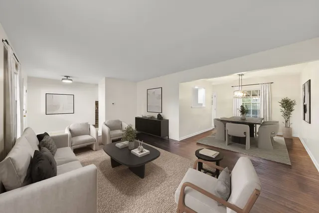 a living room with furniture couches and a dining table with wooden floor