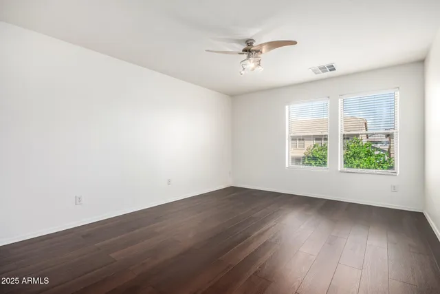 an empty room with wooden floor and a ceiling fan