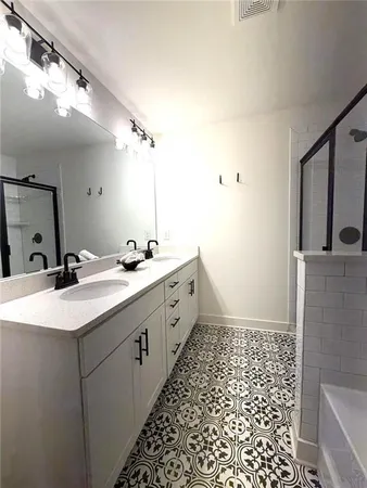 a spacious bathroom with a double vanity sink a toilet a mirror and shower
