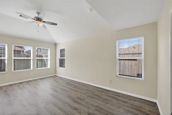 a view of an empty room with a window and wooden floor