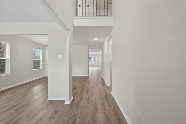 a view of a hallway with wooden floor and a bathroom
