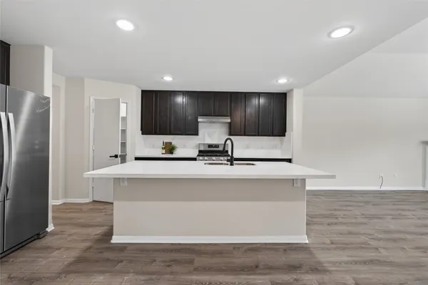 a large white kitchen with kitchen island a sink stainless steel appliances and cabinets