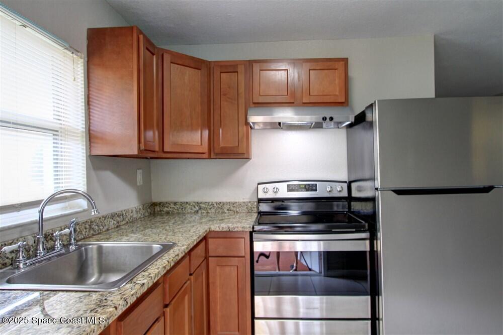 130 Roosevelt Avenue, Unit 104 Satellite Beach, FL 32937 - Photo 5 of 21 a kitchen with granite countertop a sink and a refrigerator