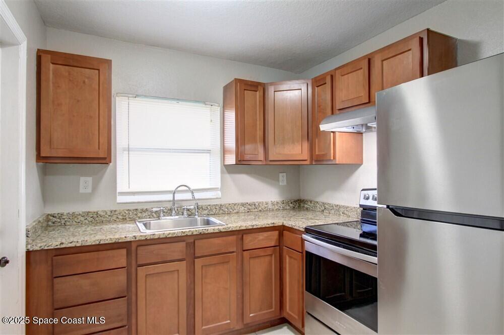 130 Roosevelt Avenue, Unit 104 Satellite Beach, FL 32937 - Photo 6 of 21 a kitchen with stainless steel appliances granite countertop a refrigerator sink and stove